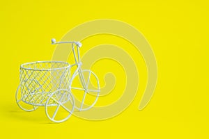 A toy bike. The idea for a postcard. Yellow background. Minimalism