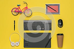 Toy bike, picture, keyboard and graphic tablet on a yellow background.