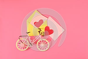 Toy bike in vintage style, two red felt hearts and postcard in a pink envelope