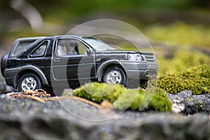 A toy black car makes its way through the off-road