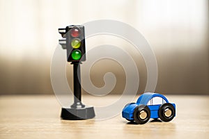 A toy blue car near a traffic light on the table.