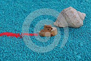 A toy boat sails on the sand with a shell