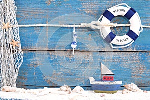 Toy boat with shells on a blue wooden background for summer, holiday, sailing concepts