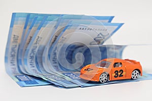 Toy car on the background of banknotes, purchase, insurance and the cost of car ownership