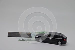 A toy car and banknotes lie on a kitchen electronic scale next to a calculator, the cost of operating a car