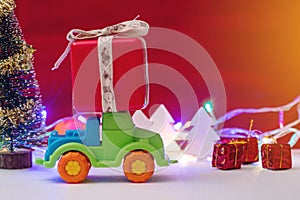 Toy car carries gifts in the Christmas and new year's eve on a red background. Holiday shopping and discounts