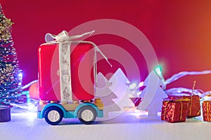 Toy car carries gifts in the Christmas and new year's eve on a red background. Holiday shopping and discounts