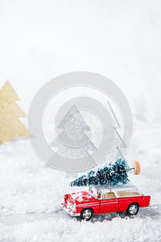 Toy car carrying christmas tree in a snow forest