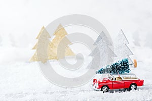 Toy car carrying christmas tree in a snow forest