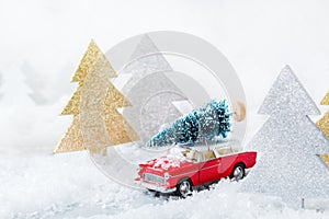 Toy car carrying christmas tree in a snow forest