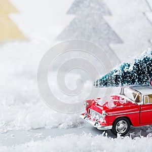 Toy car carrying christmas tree in a snow forest