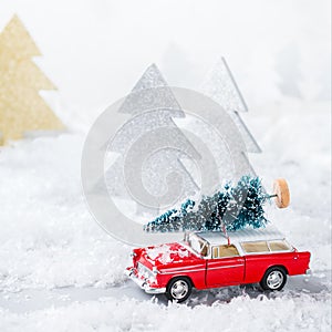 Toy car carrying christmas tree in a snow forest