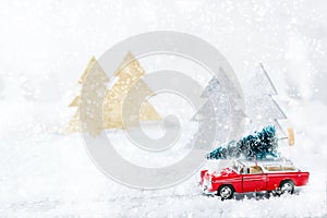 Toy car carrying christmas tree in a snow forest