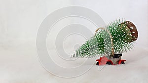 Toy car carrying a Christmas tree in a snowy landscape. Space for text.