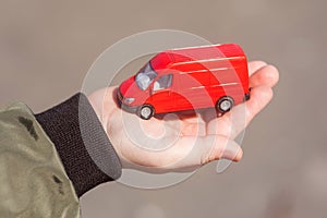 Toy car on a child`s hand. Cargo delivery van. Red toy truck. A child playing a toy car