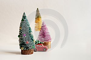 Toy car with chrstmas tree and three small colorful christmas trees