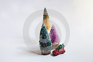 Toy car with chrstmas tree and three small colorful christmas trees