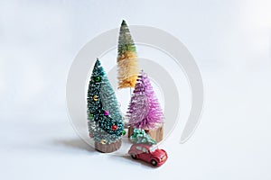 Toy car with chrstmas tree and three small colorful christmas trees