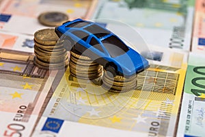 Toy car on coin and euro bills