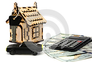 Toy car, dollars, calculator and toy house with a key. White background. Business concept. Save money to buy a house or a car.