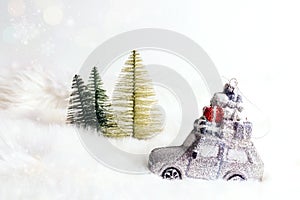 Toy car with gifts and fir trees on white fur background that looks like snow. Christmas and New year holiday celebration concept