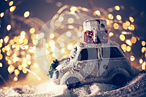 Toy car with gifts on the roof standing in snow. Christmas