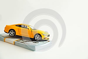 Toy Car Hanging on a Stack of Money on a White Background. Concept Car Expenses, loan payment