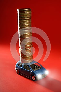 Toy car with huge column of golden coins over red