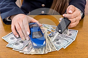Toy car and keys in female hands on dollar notes