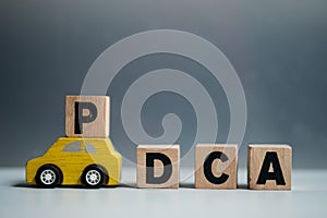 Toy car moves a wooden cube with the letter P to complete the word PDCA