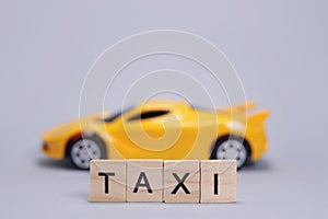 Toy car and the taxi made of wooden letters, cab passenger transportation concept