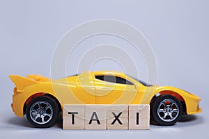 Toy car and the taxi made of wooden letters, cab passenger transportation concept