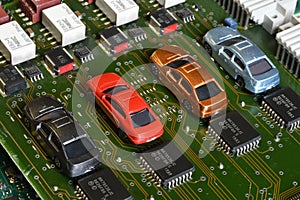 Toy cars on electronic board and microchip. The shortage of microchips and semiconductors creates a shortage of new cars.