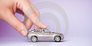 Toy child car in woman`s hand. Purchase insurance bank loan travel where to go trip journey concept. on violet