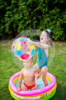 Toy for children games. Children playing with Inflatable rubber beach ball. in water pool. Summer holiday. Boy and Girl Playing in