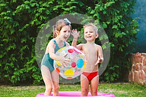 Toy for children games. Children playing with Inflatable rubber beach ball. in water pool. Summer holiday. Boy and Girl Playing in