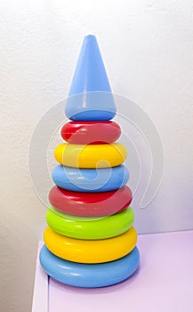 Toy children`s pyramid for development of intelligence and motility on light textural background