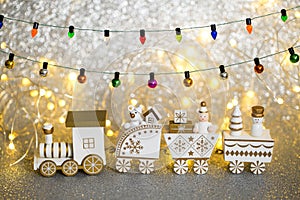 Toy Christmas train with gifts and figures on it. Miniature winter toy with lights and garland