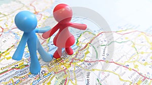 A toy couple standing over Edinburgh on a map of Scotland