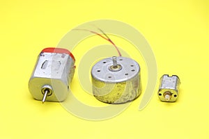 Toy dc motor along with DVD motor and micro servo motor on yellow background. Single shaft dc motor used in electronics projects