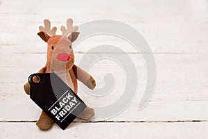 Toy deer with black friday tag on white wood background with copy space