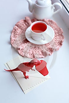 Toy dinosuar biting paper craft origami red heart, surreal trendy concept of valentines day, living coral color