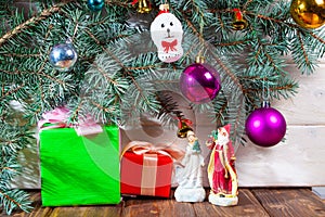 A toy dog in Santa hat and Christmas gifts on the background of coniferous branches