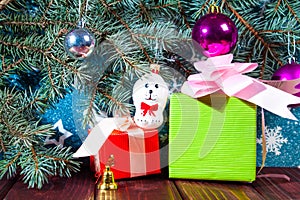 A toy dog in Santa hat and Christmas gifts on the background of coniferous branches