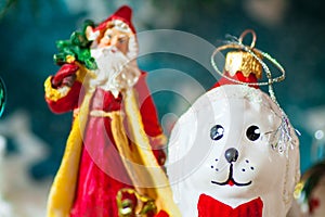 A toy dog in Santa hat and Christmas gifts on the background of coniferous branches