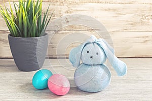 Toy Easter bunny and painted eggs on a wooden background