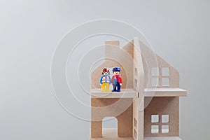 Toy figures of men and women standing next to each other in a wooden house. Symbol of family