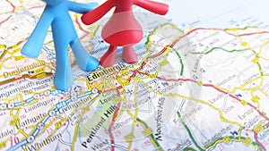 A toy figures standing over Edinburgh on a map of Scotland