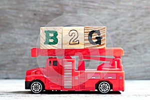 Toy fire ladder truck hold block in word B2G abbreviation of business to government on wood background