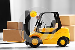 Toy forklift with boxes near laptop. Logistics and wholesale concept